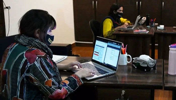 Two women are using their laptops in an office. — AFP/File